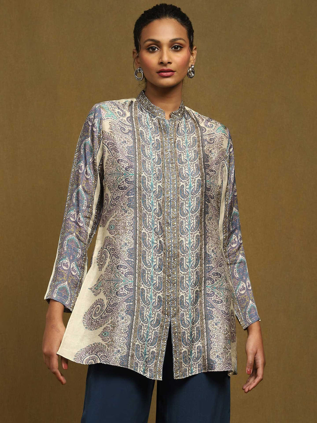 Woman wearing a patterned white kurta against a brown background