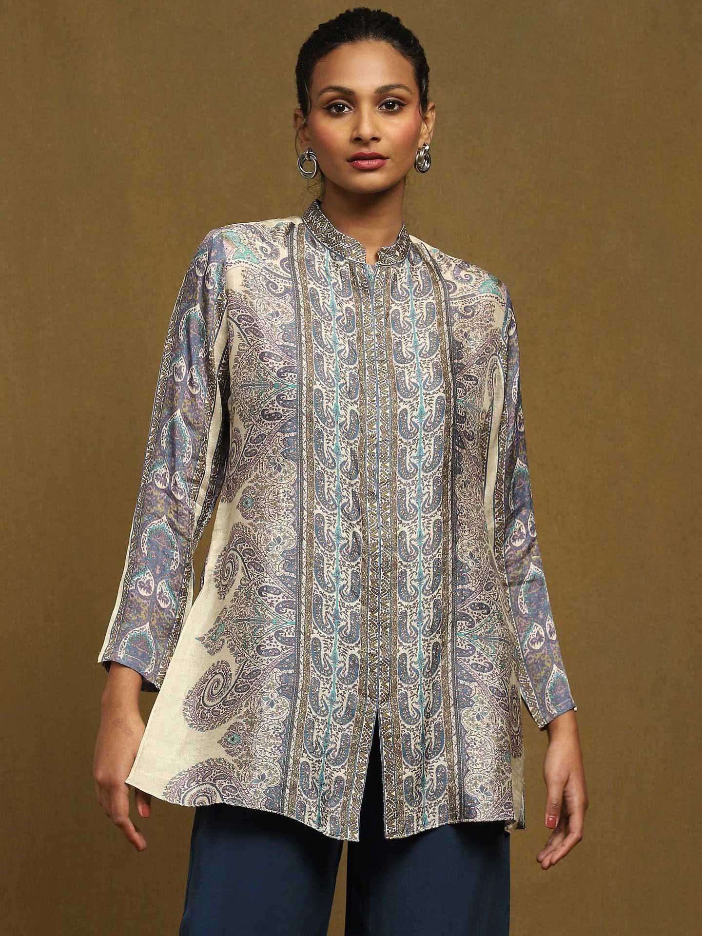 Woman wearing a patterned white kurta against a brown background