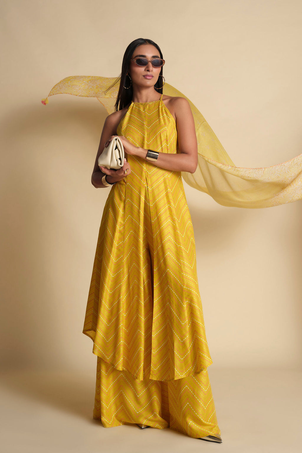 Woman in a yellow dress holding a white bag against a beige background