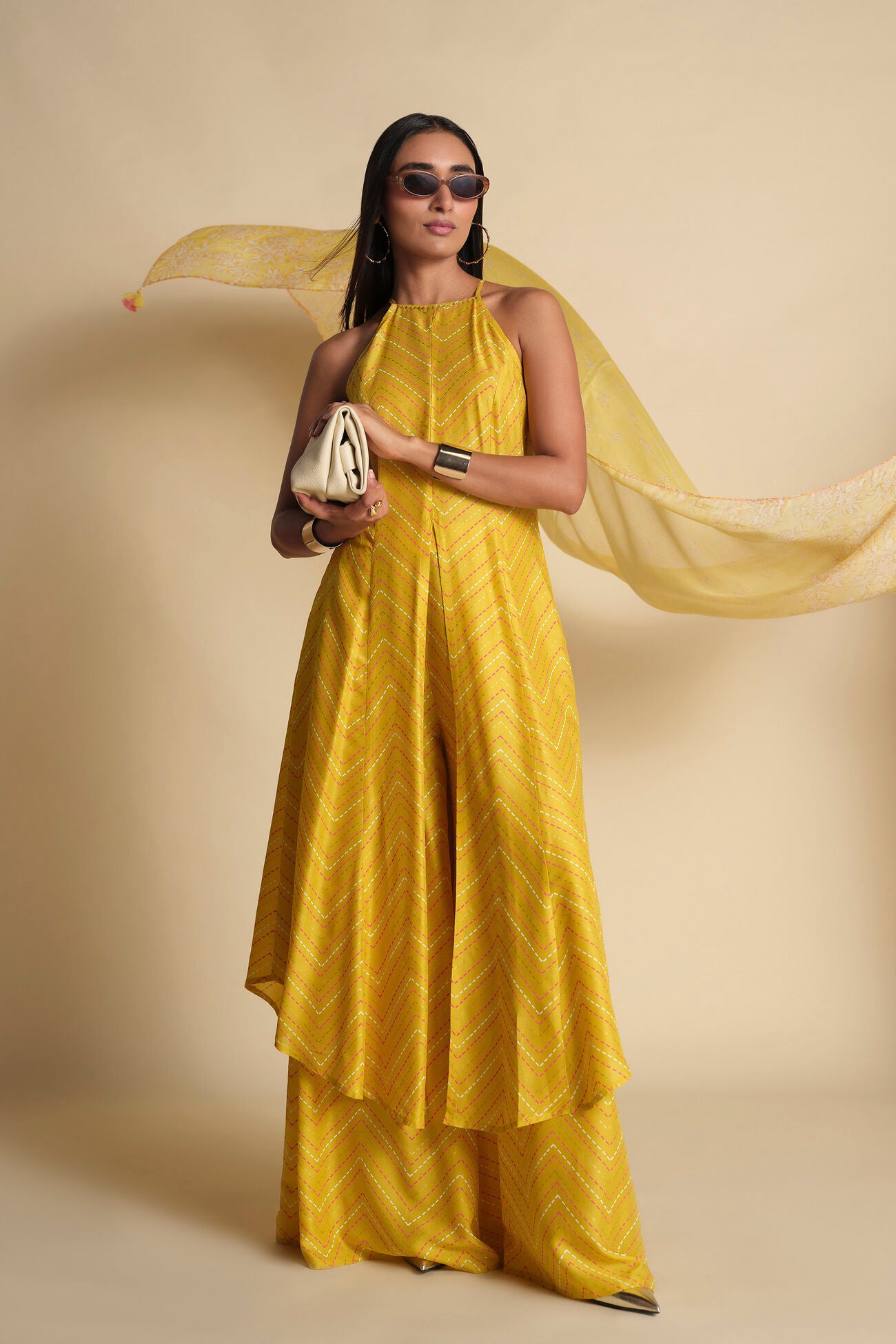 Woman in a yellow dress holding a white bag against a beige background