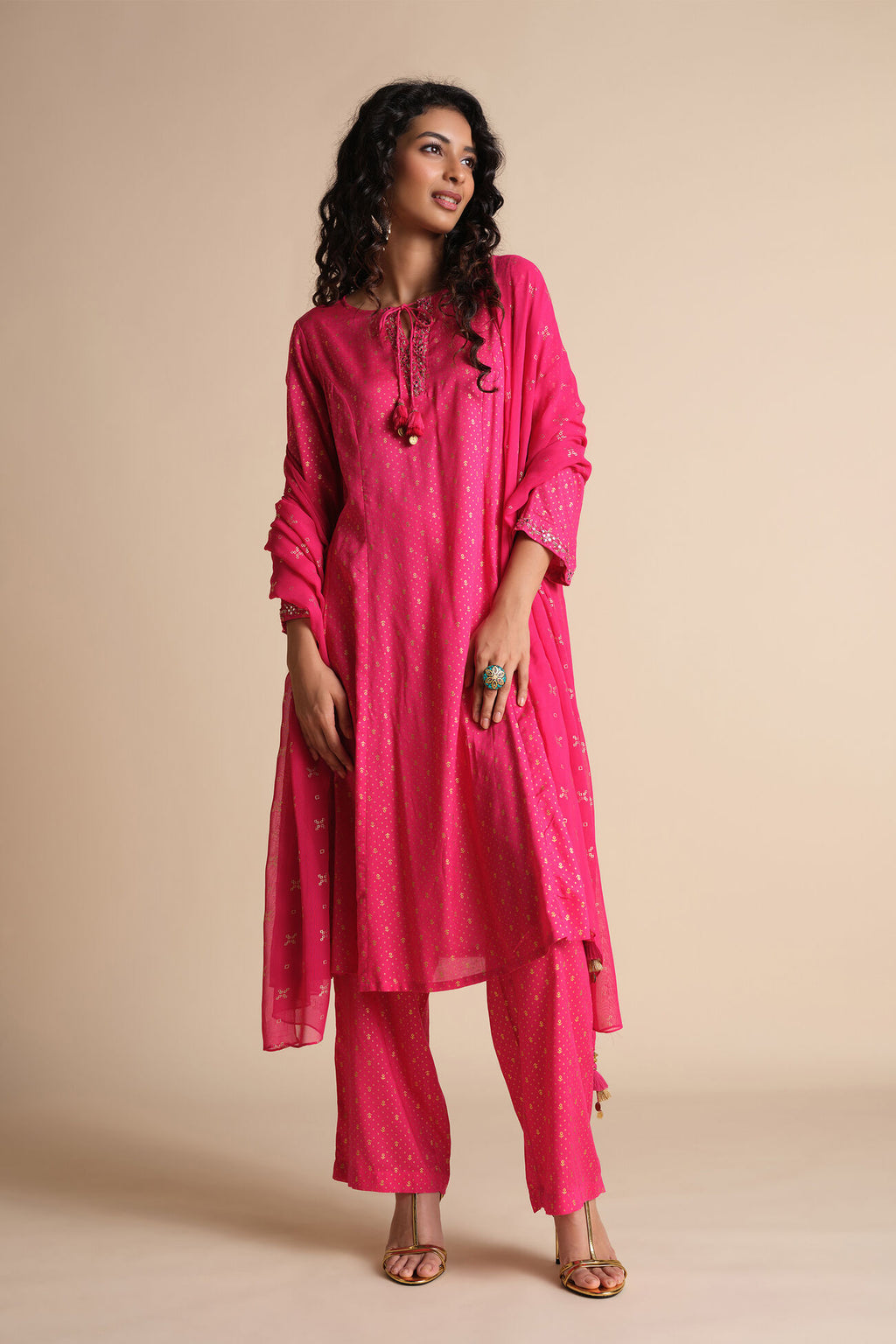 Woman wearing a bright pink traditional outfit on a beige background