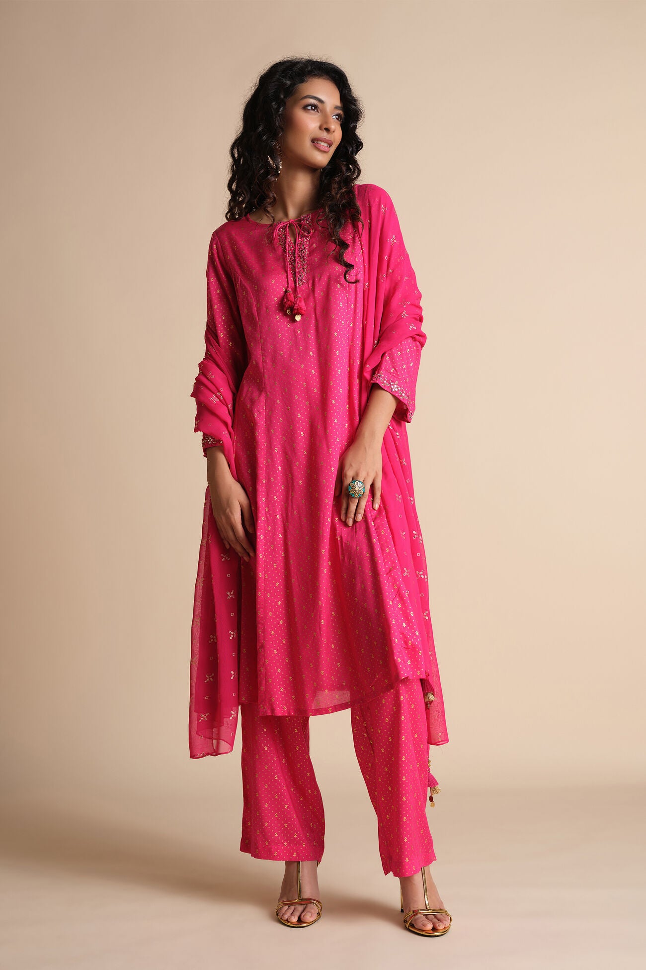 Woman wearing a bright pink traditional outfit on a beige background