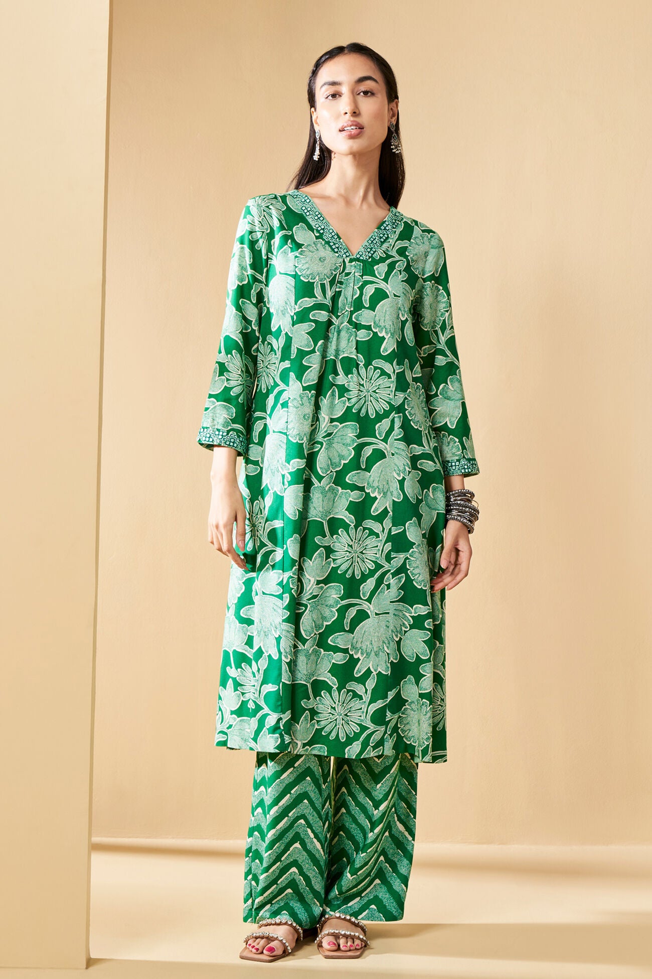 Woman wearing a green floral outfit against a beige background