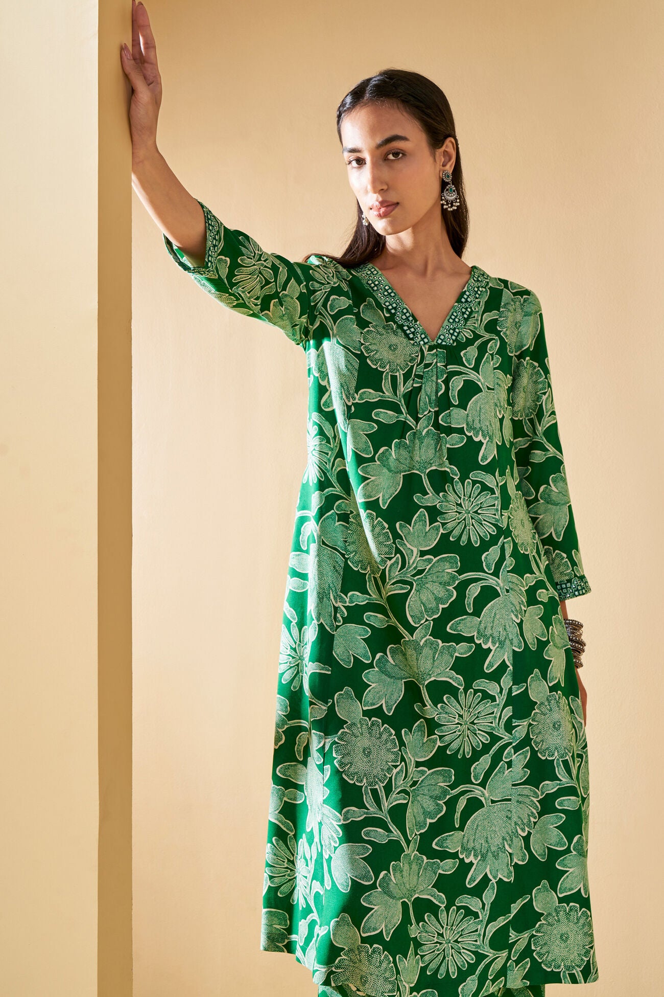 Woman wearing a green floral dress against a beige background