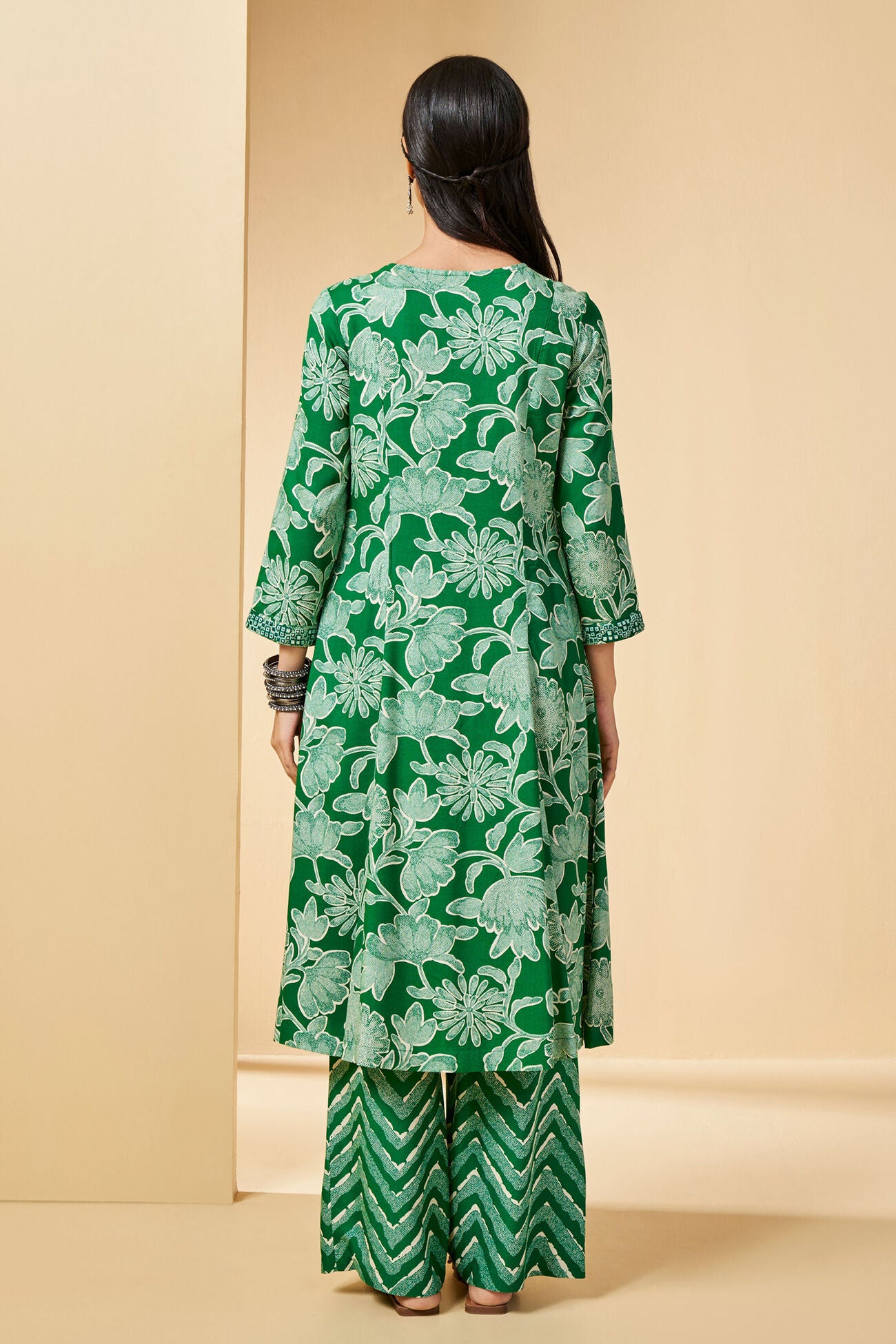 Woman wearing a green floral dress against a beige background