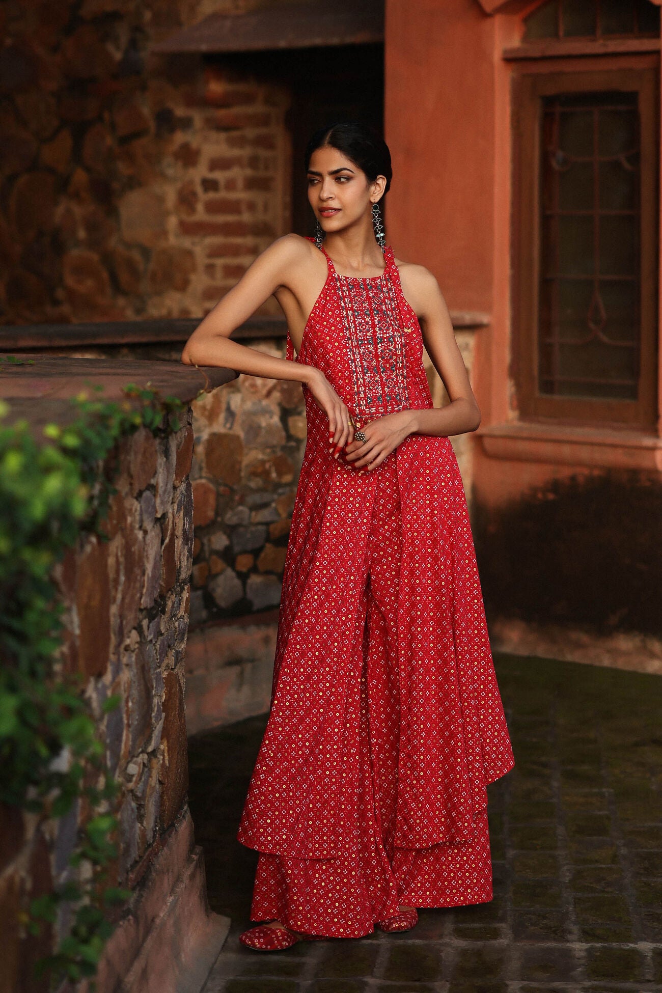 Woman in a red dress standing against a stone wall.