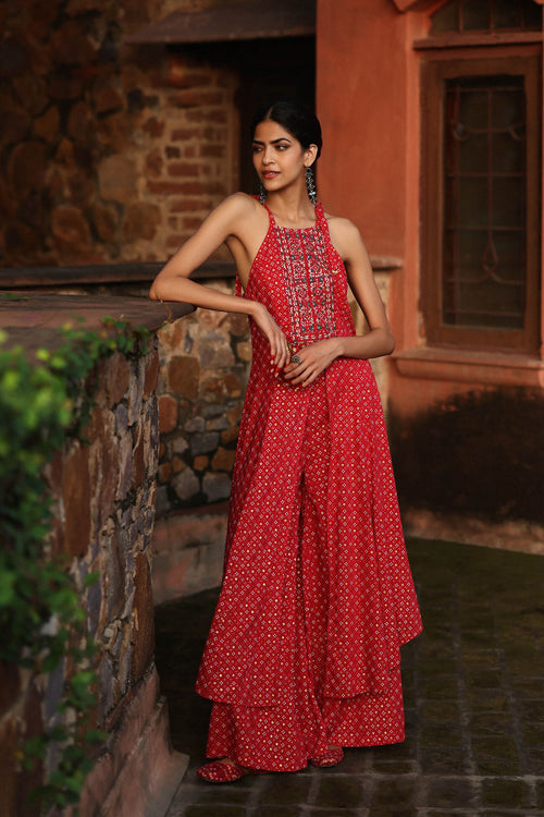 Woman in a red dress standing against a stone wall.