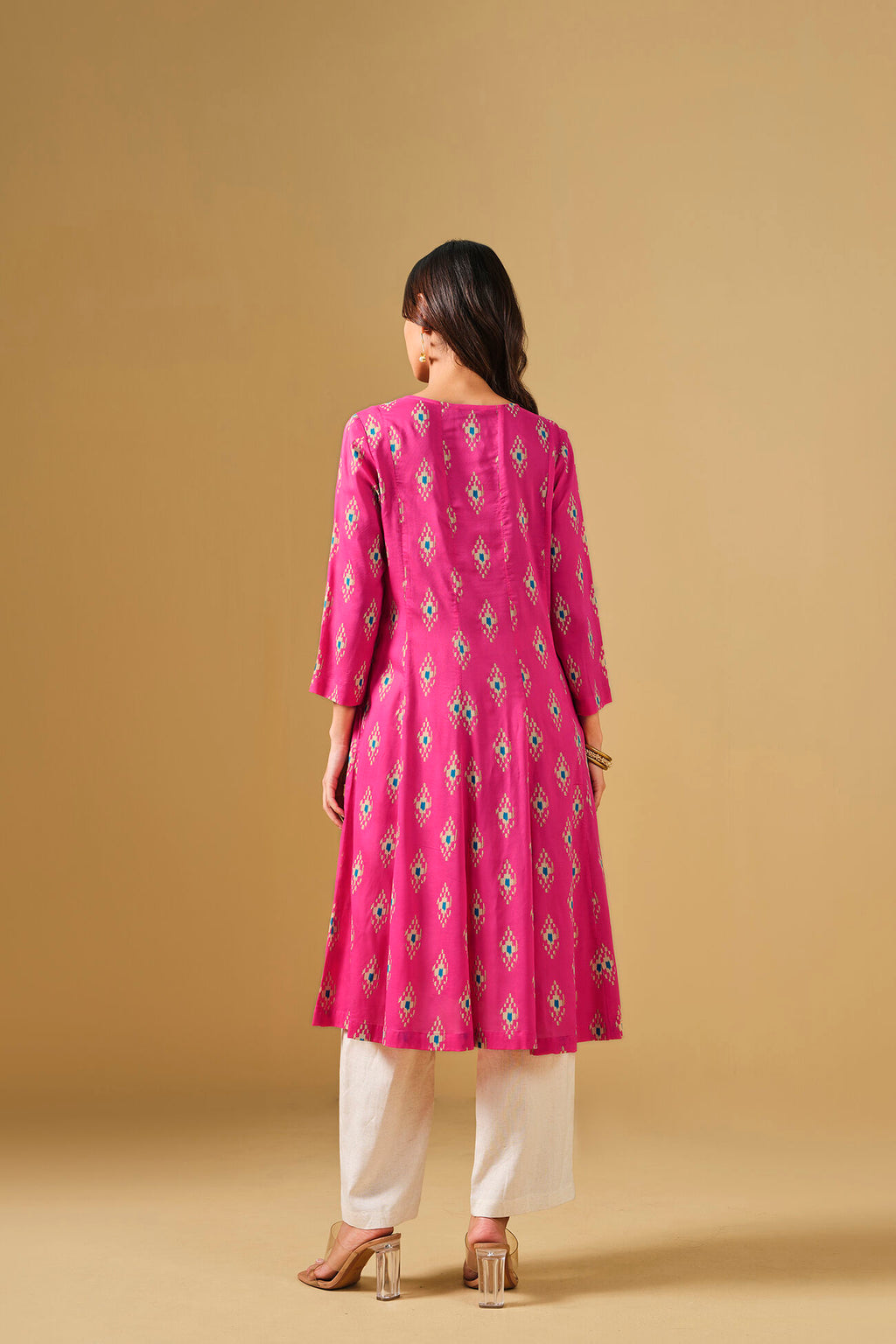 Woman wearing a pink kurta with white pants on a beige background