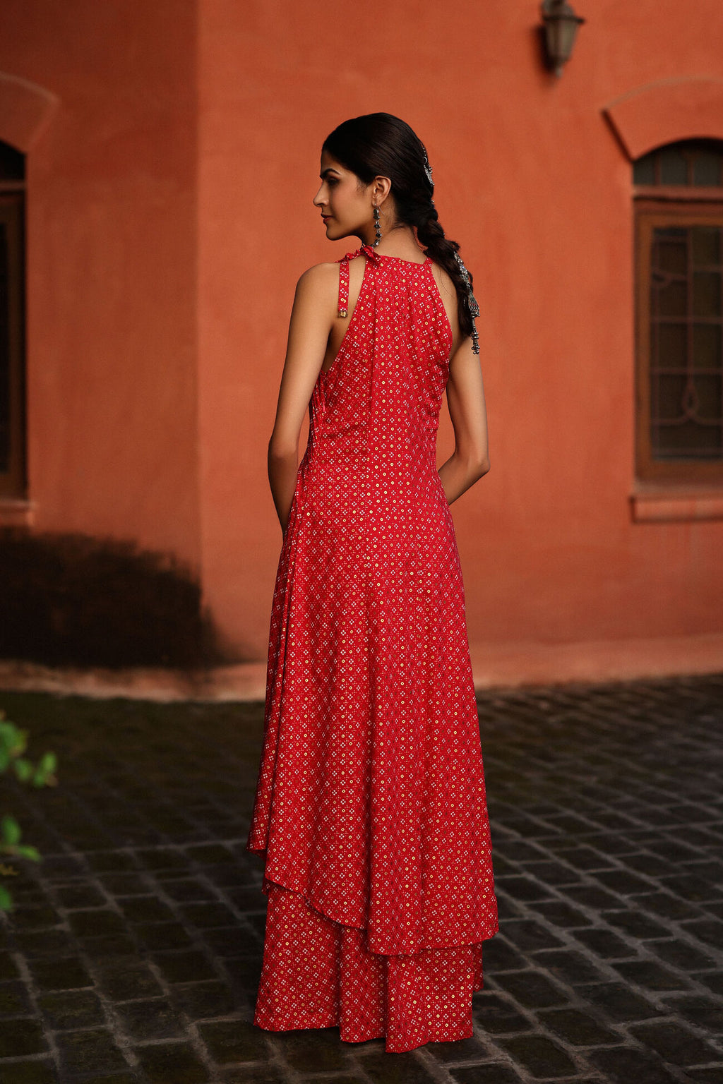 Woman in a red dress standing in front of an orange wall.