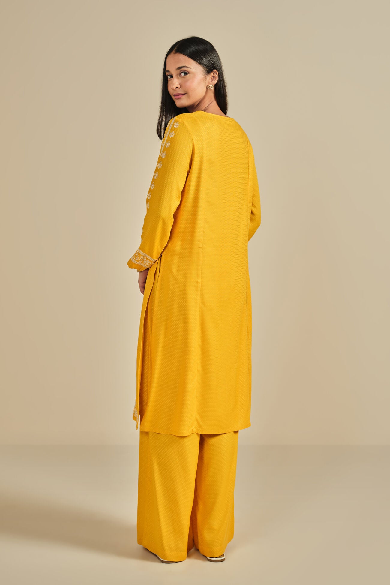 Woman wearing a yellow traditional outfit on a beige background