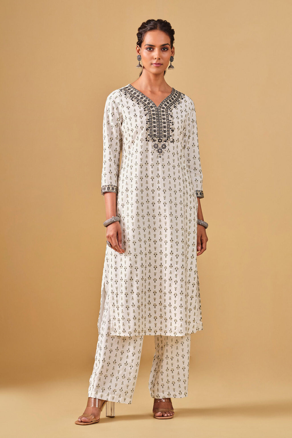 Woman wearing a white kurta with black patterns on a beige background
