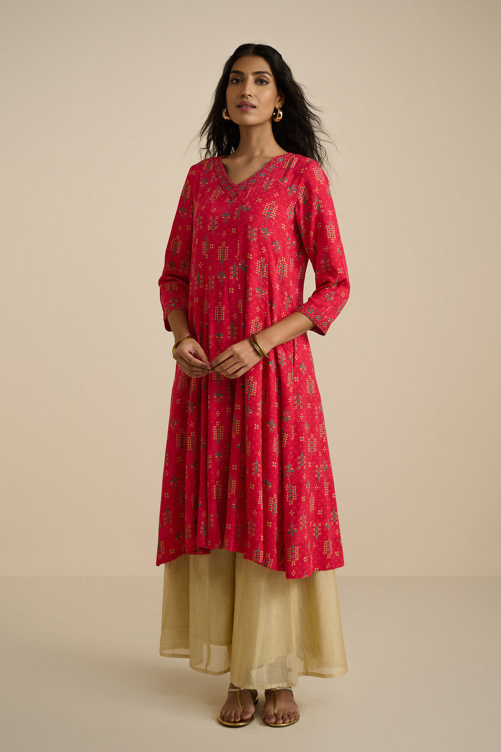 Woman wearing a red kurta with beige pants on a beige background