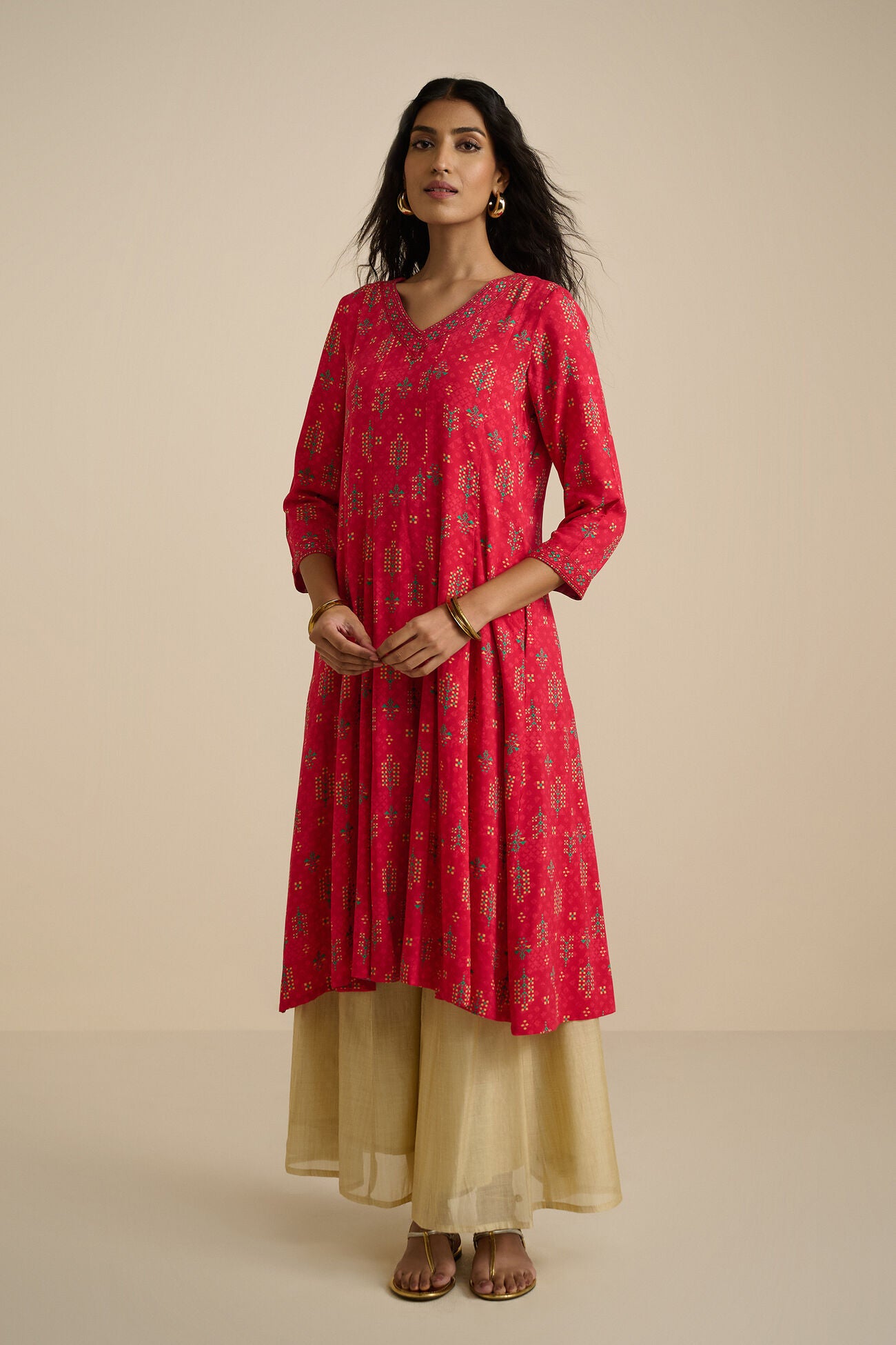 Woman wearing a red kurta with beige pants on a beige background