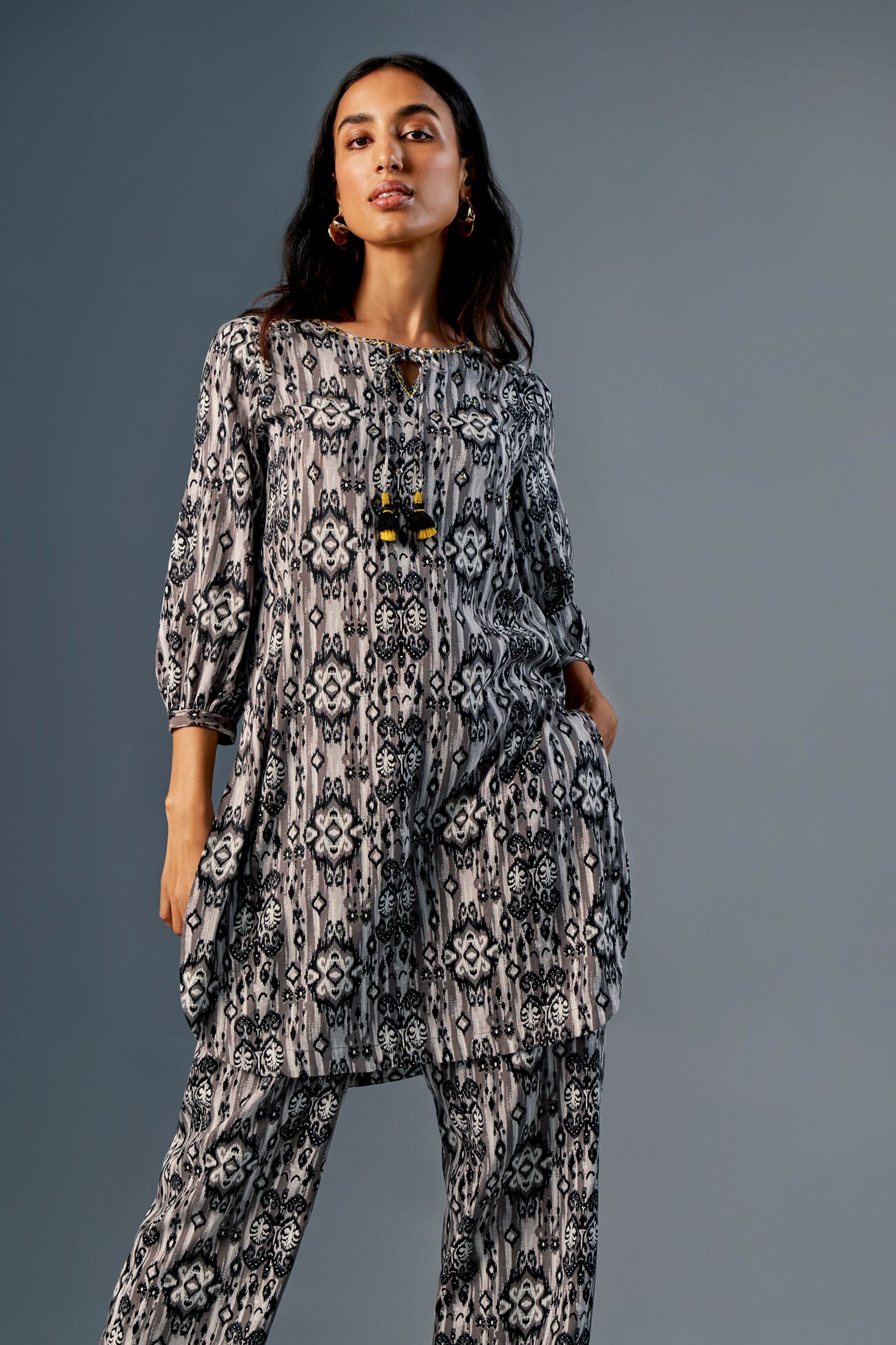 Woman wearing a black and white patterned outfit against a gray background