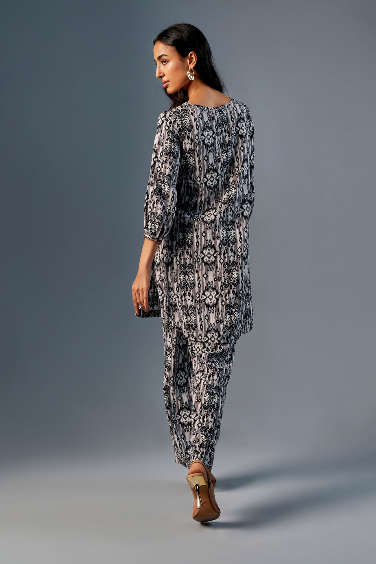 Woman wearing a patterned outfit against a gray background