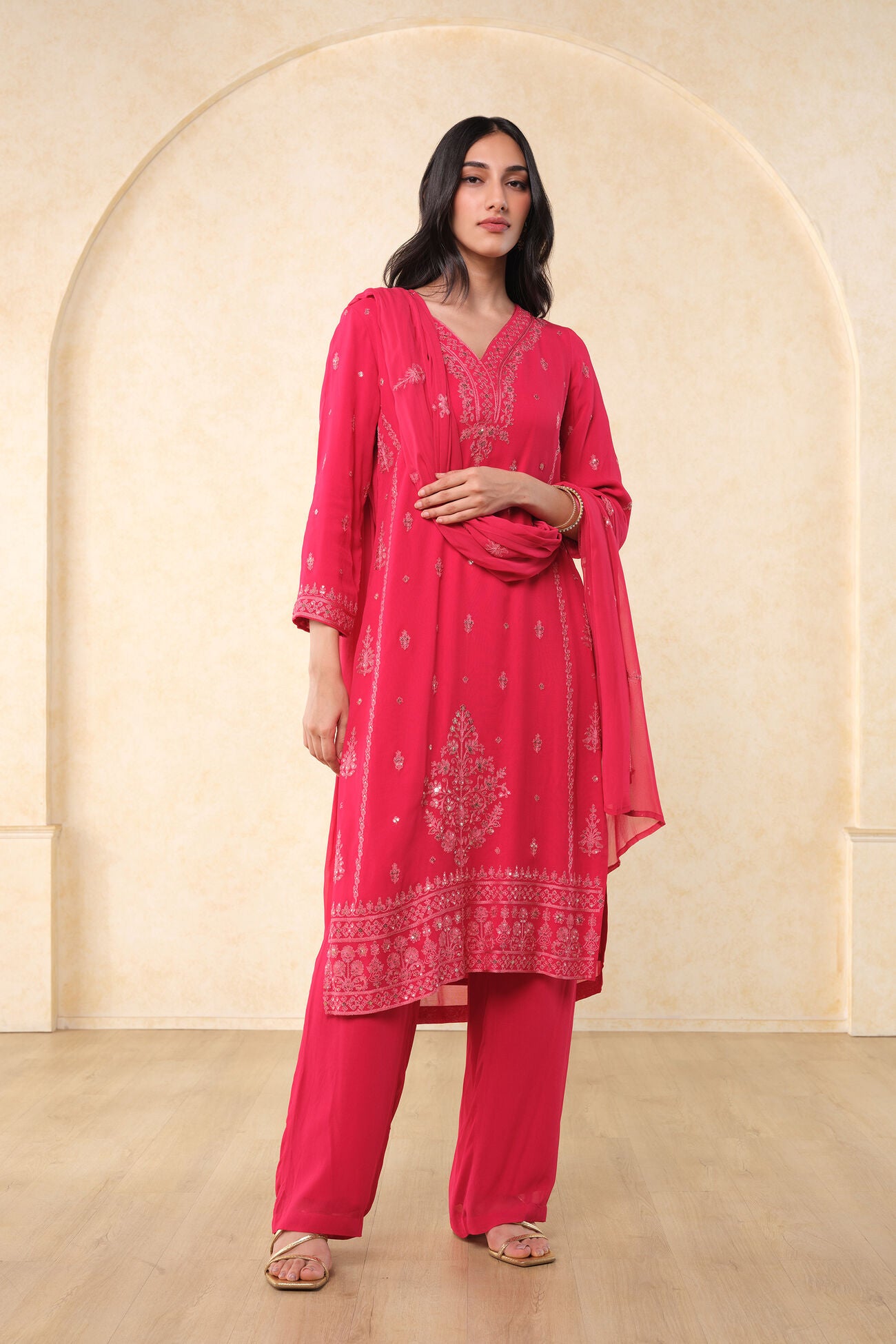 Woman wearing a pink traditional outfit with a beige archway background