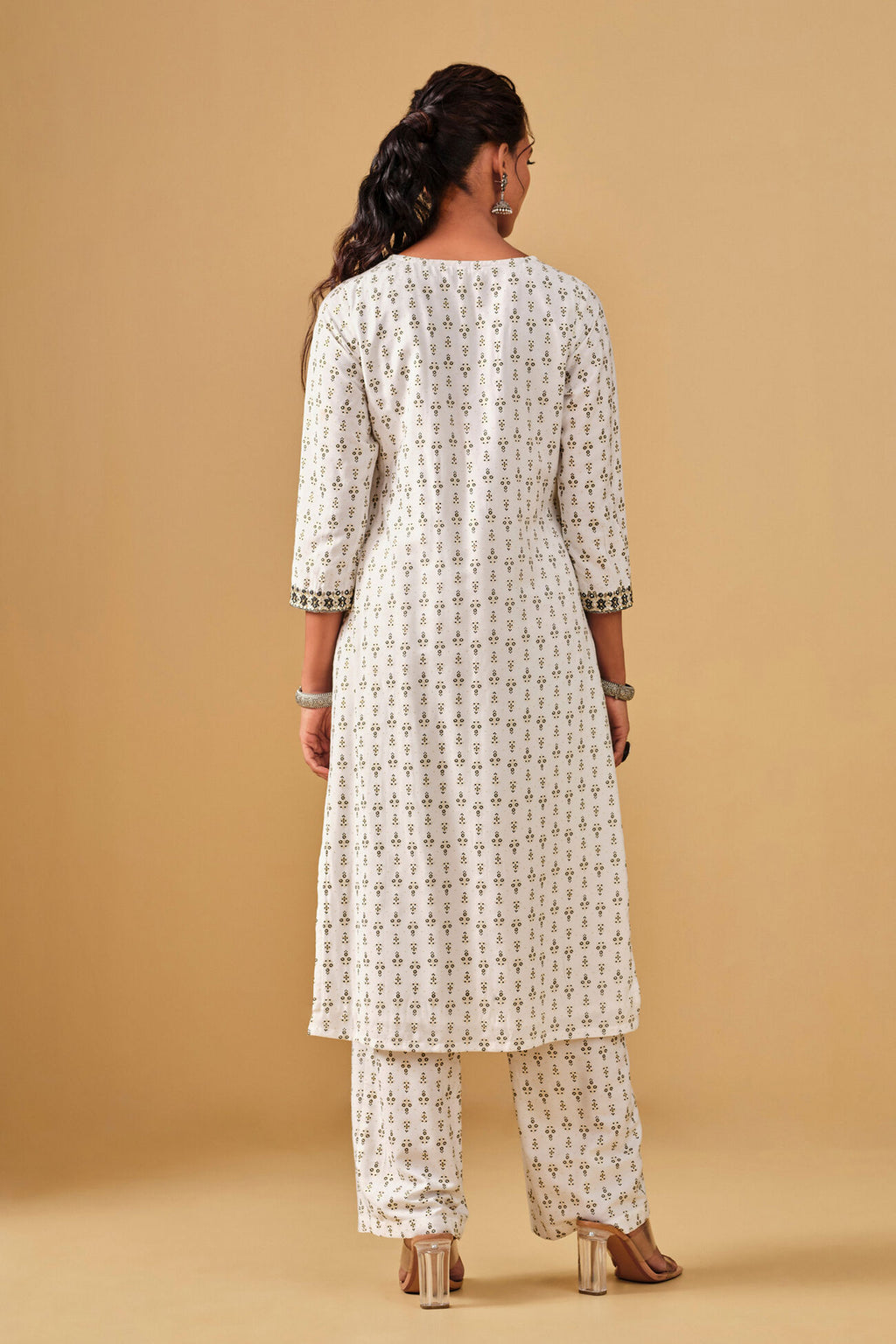 Woman wearing a white patterned kurta with pants on a beige background