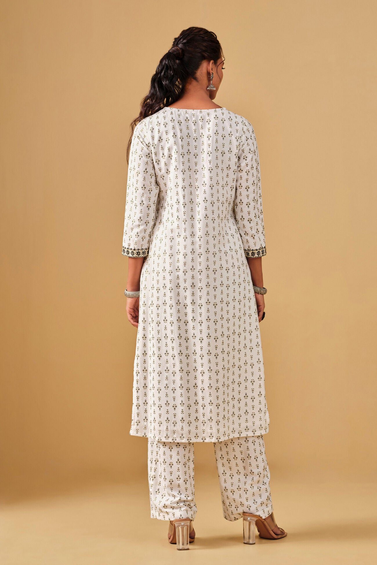 Woman wearing a white patterned kurta with pants on a beige background