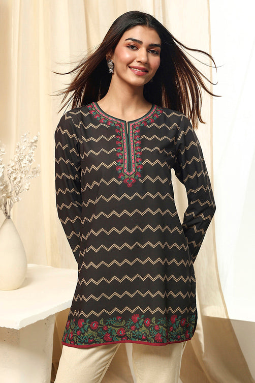 Woman wearing a black and beige patterned kurta with white pants against a neutral background
