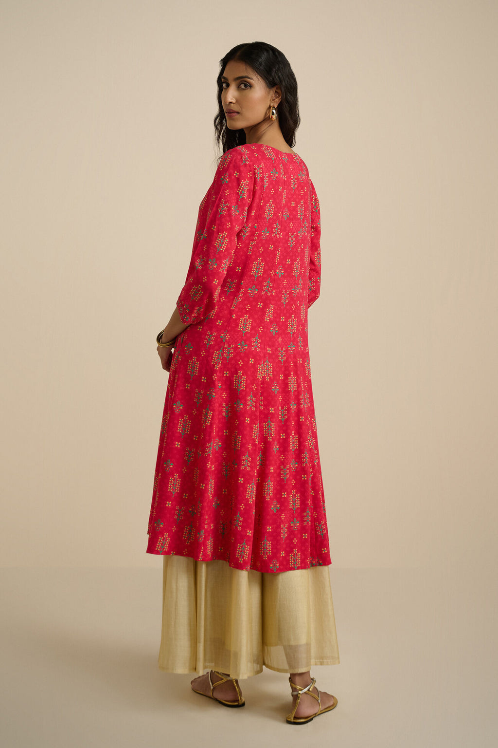 Woman wearing a red and gold traditional outfit on a beige background