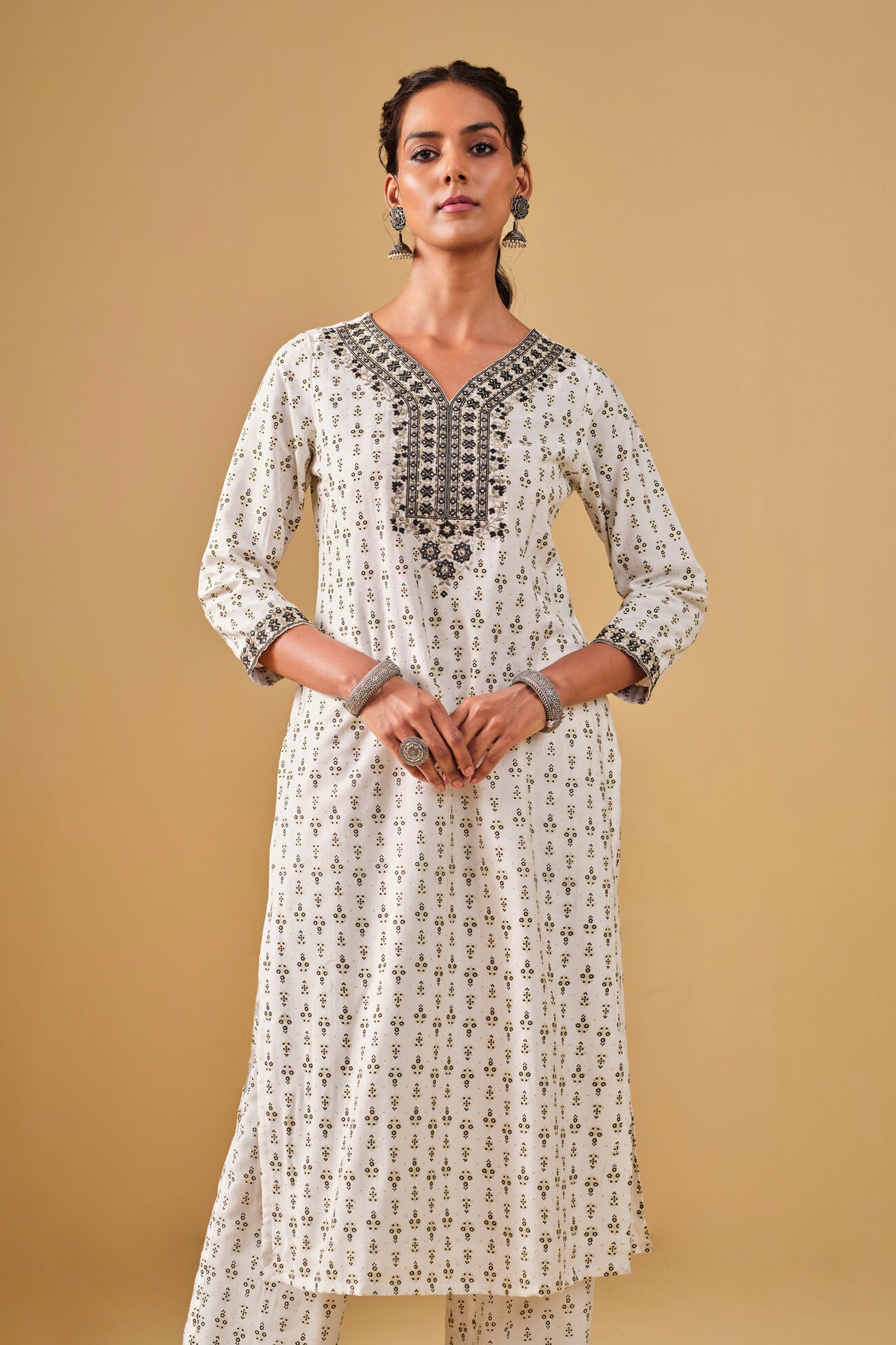 Woman wearing a white patterned kurta with pants on a beige background