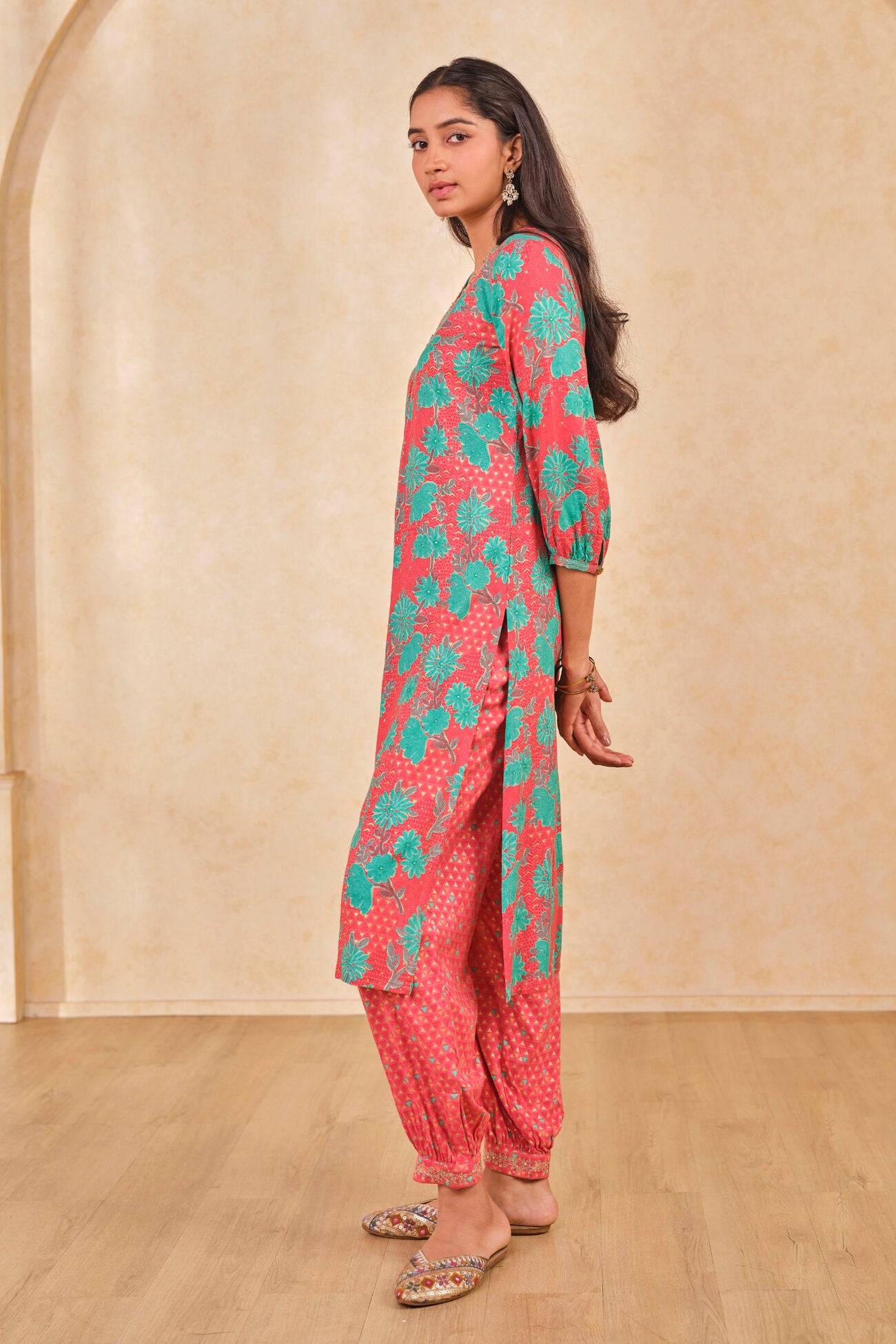 Woman wearing a pink and green traditional outfit with a beige background