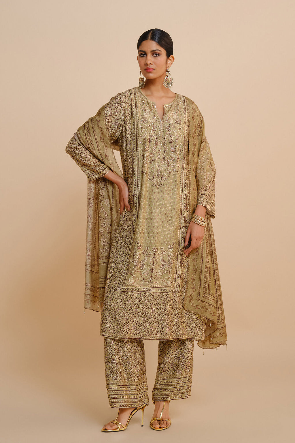 Woman wearing a traditional beige embroidered outfit on a beige background