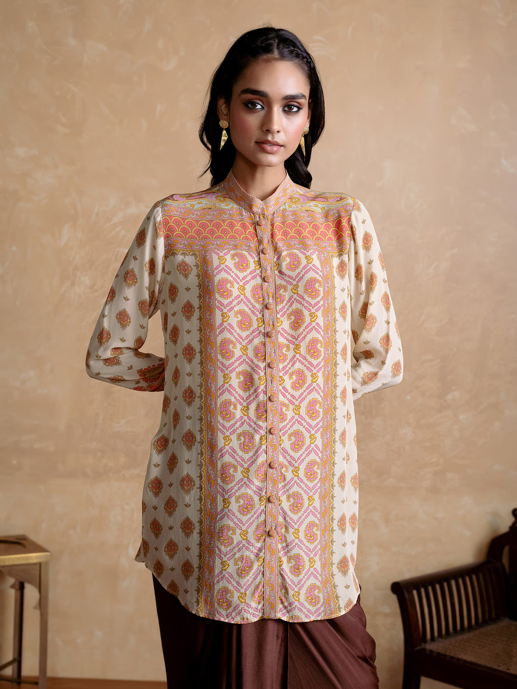 Woman wearing a patterned shirt against a beige wall