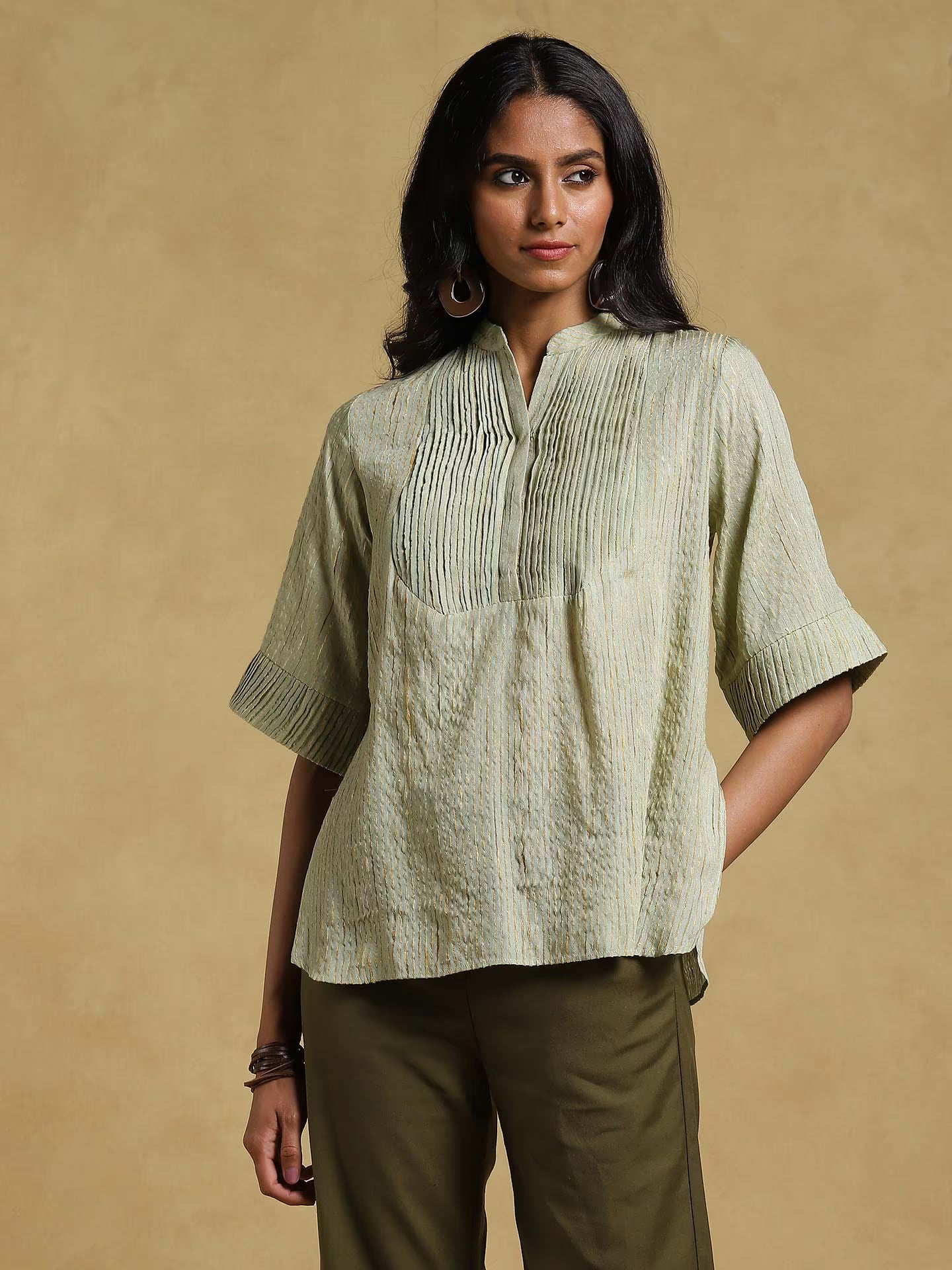 Woman wearing a light green textured blouse with a beige background