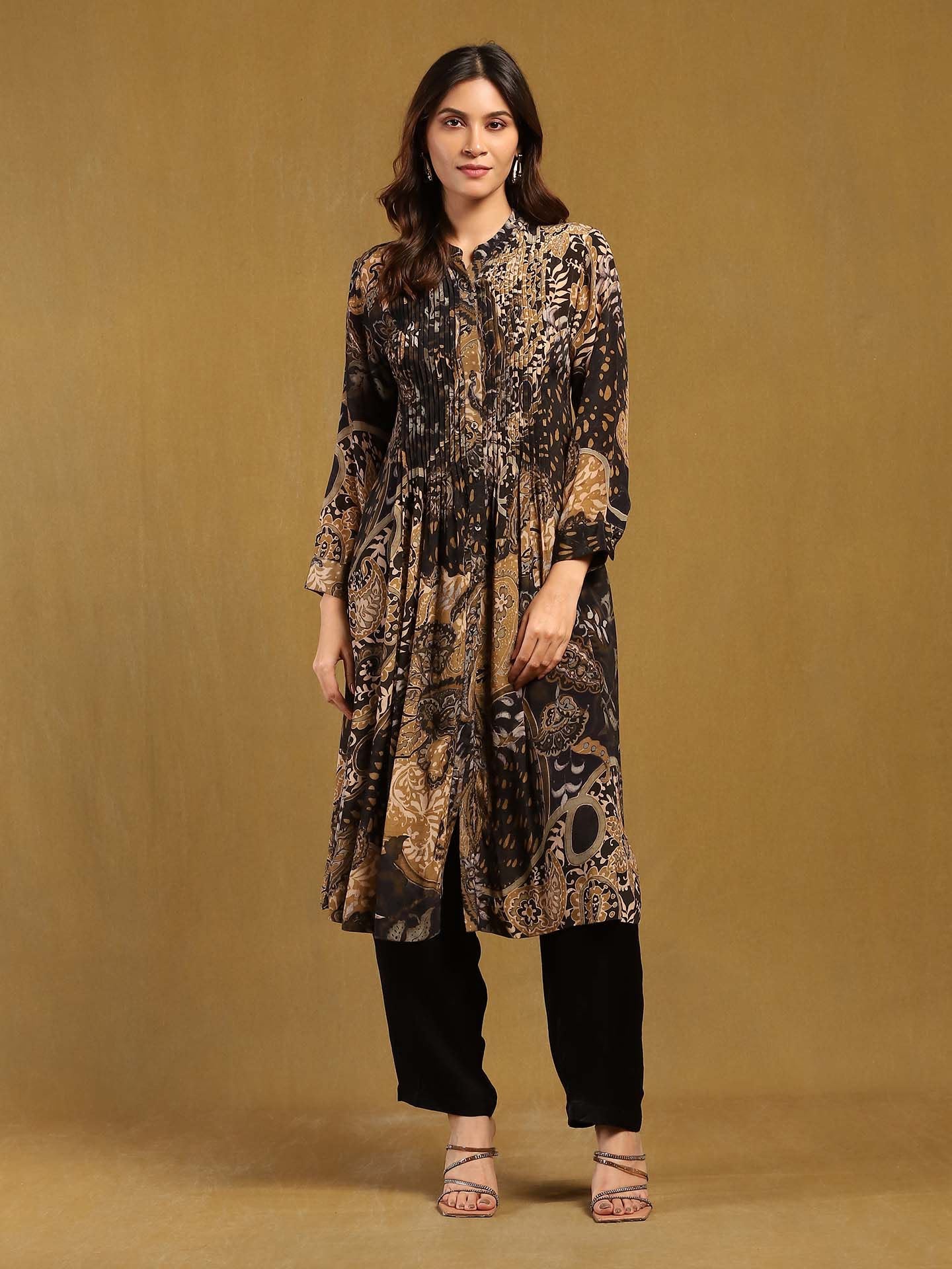 Woman wearing a patterned long dress and black pants on a beige background