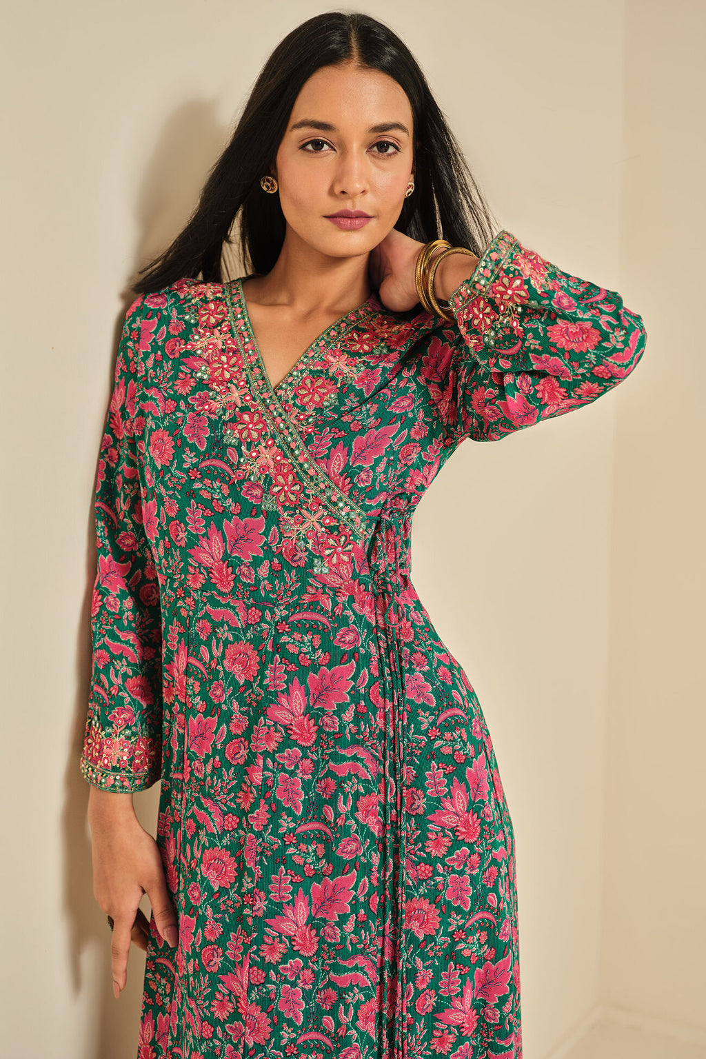 Woman wearing a floral dress with long sleeves against a beige background