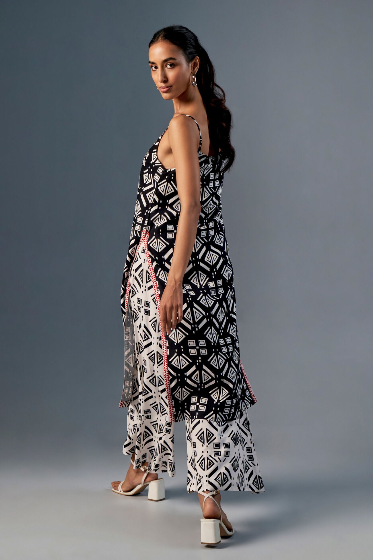 Woman wearing a black and white patterned dress against a gray background