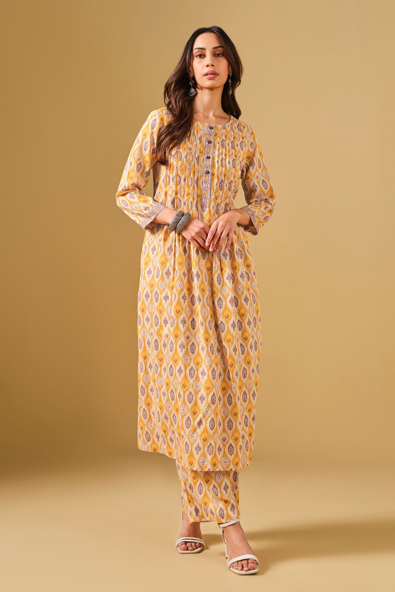 Woman wearing a yellow patterned dress against a beige background