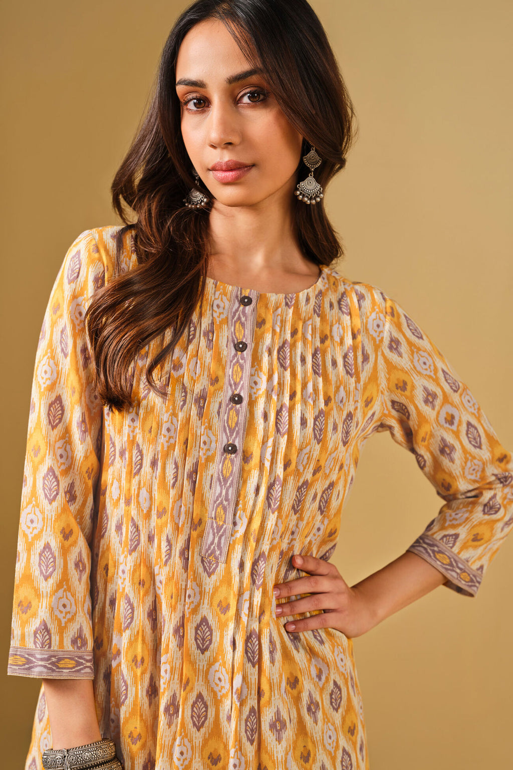 Woman wearing a yellow patterned dress against a beige background