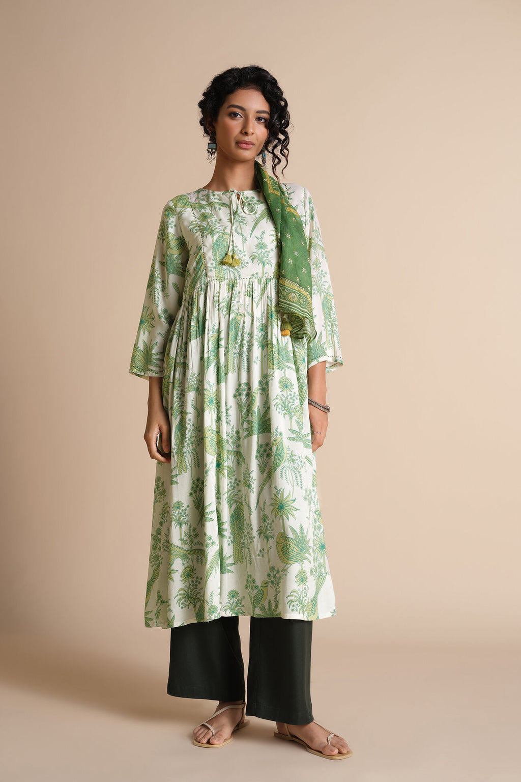 Woman wearing a green and white floral dress with a matching scarf on a beige background