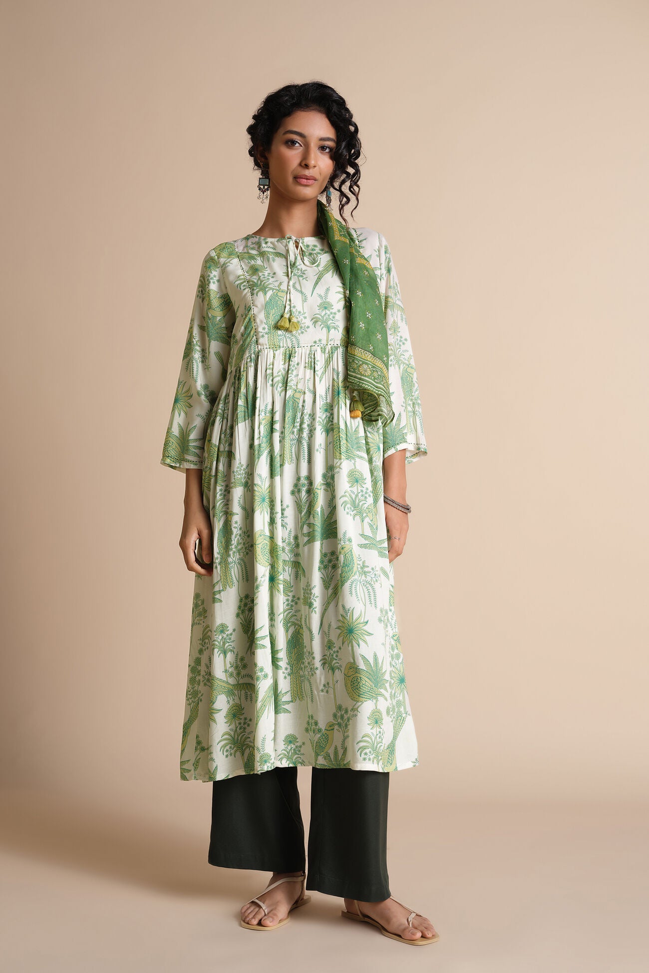 Woman wearing a green and white floral dress with a matching scarf on a beige background