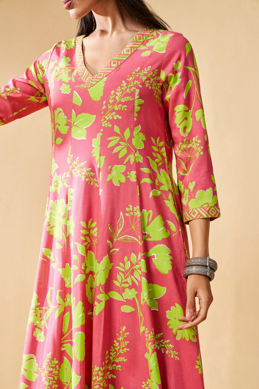Pink dress with green floral pattern on a beige background