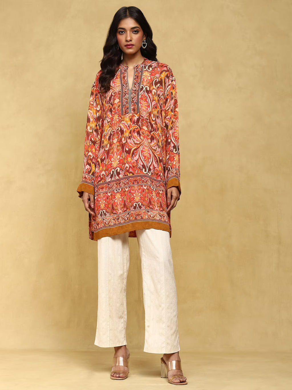 Woman wearing a patterned orange and white outfit on a beige background