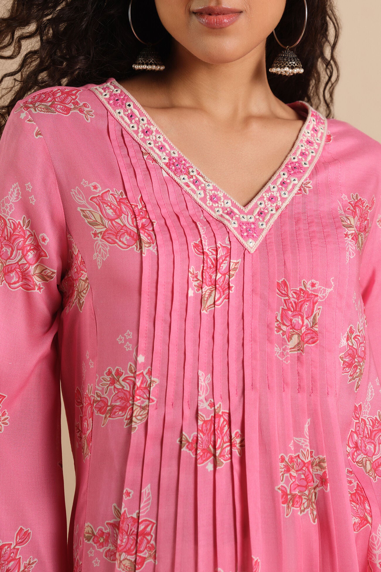 Close-up of a pink traditional outfit with floral embroidery on a beige background