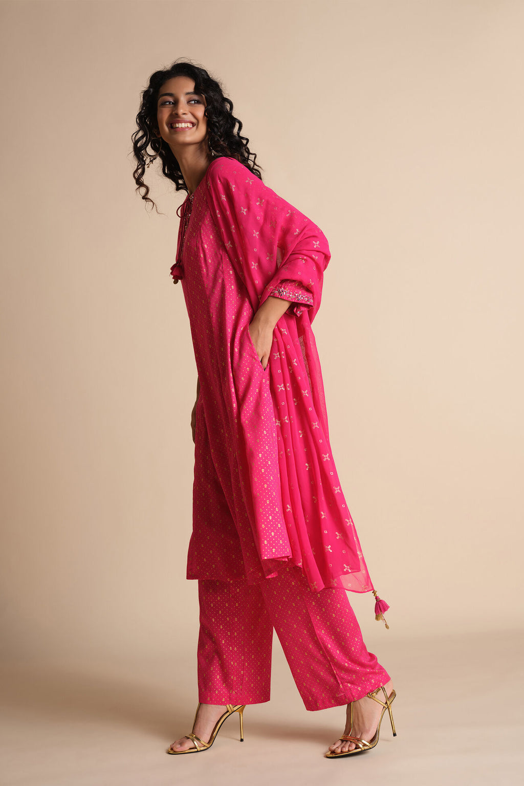Woman wearing a pink traditional outfit with a dupatta on a beige background