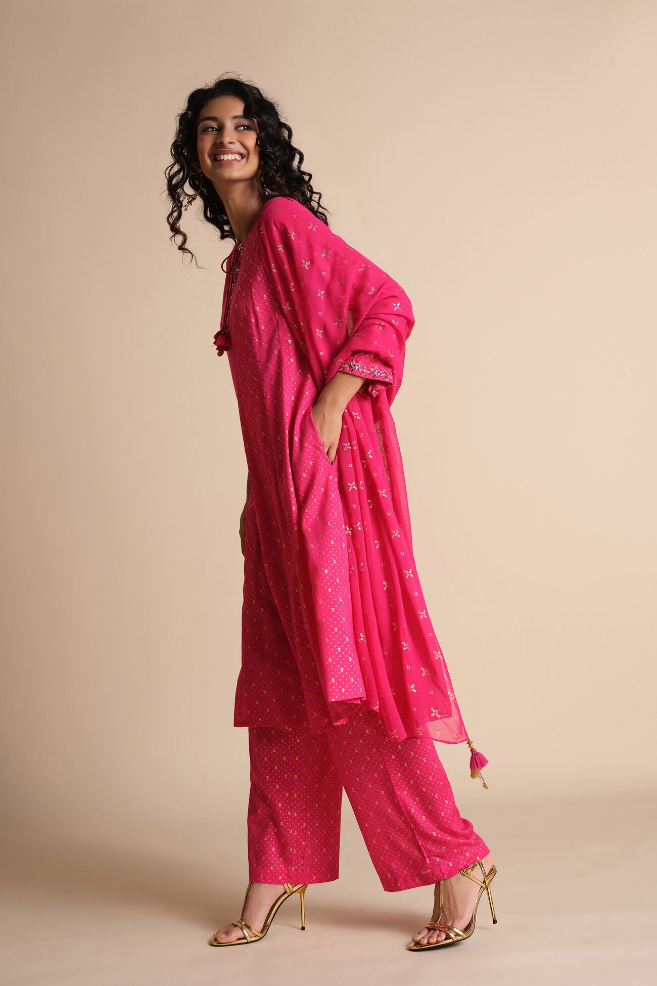 Woman wearing a pink traditional outfit with a dupatta on a beige background