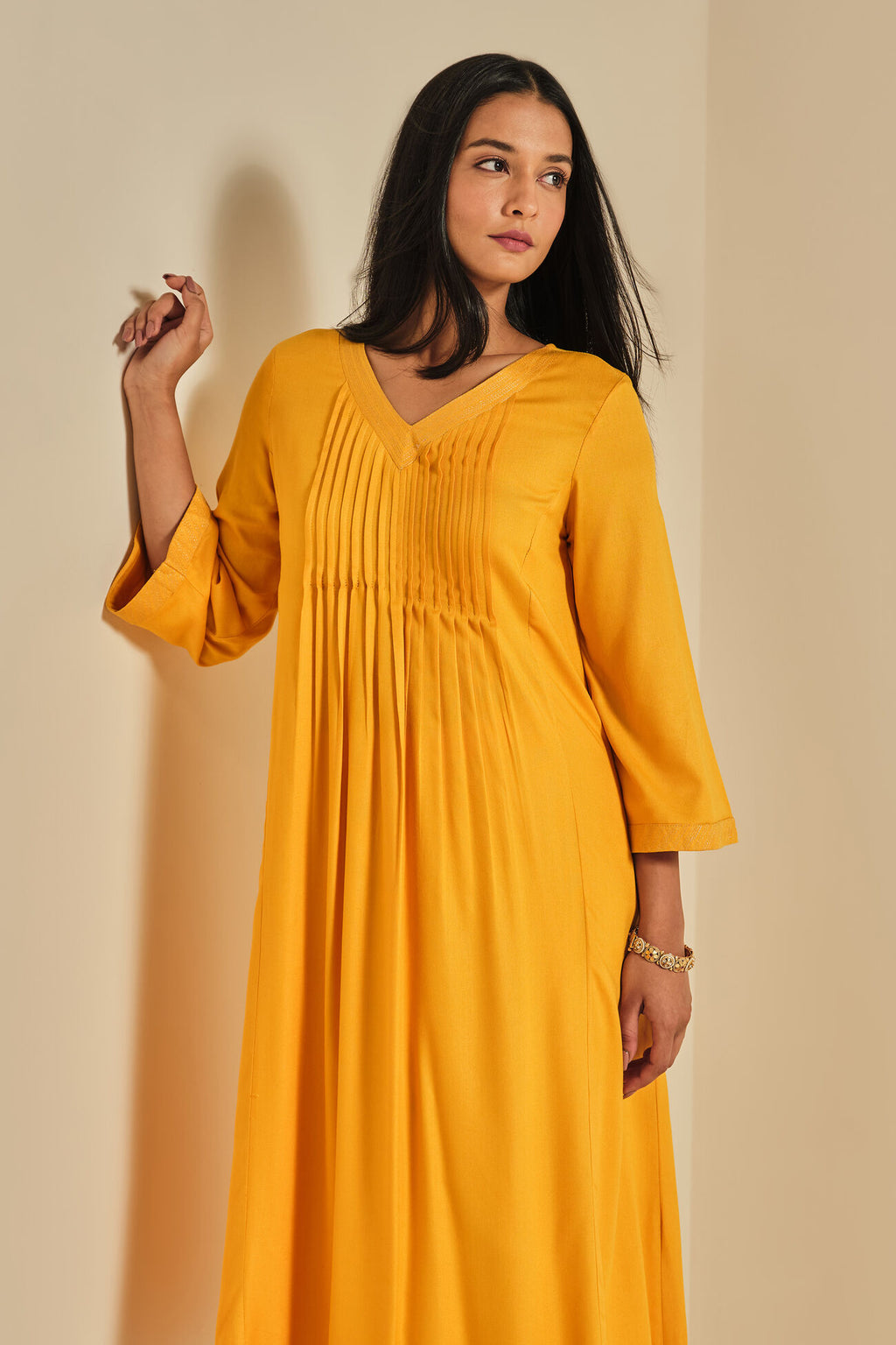 Woman wearing a yellow dress against a beige background
