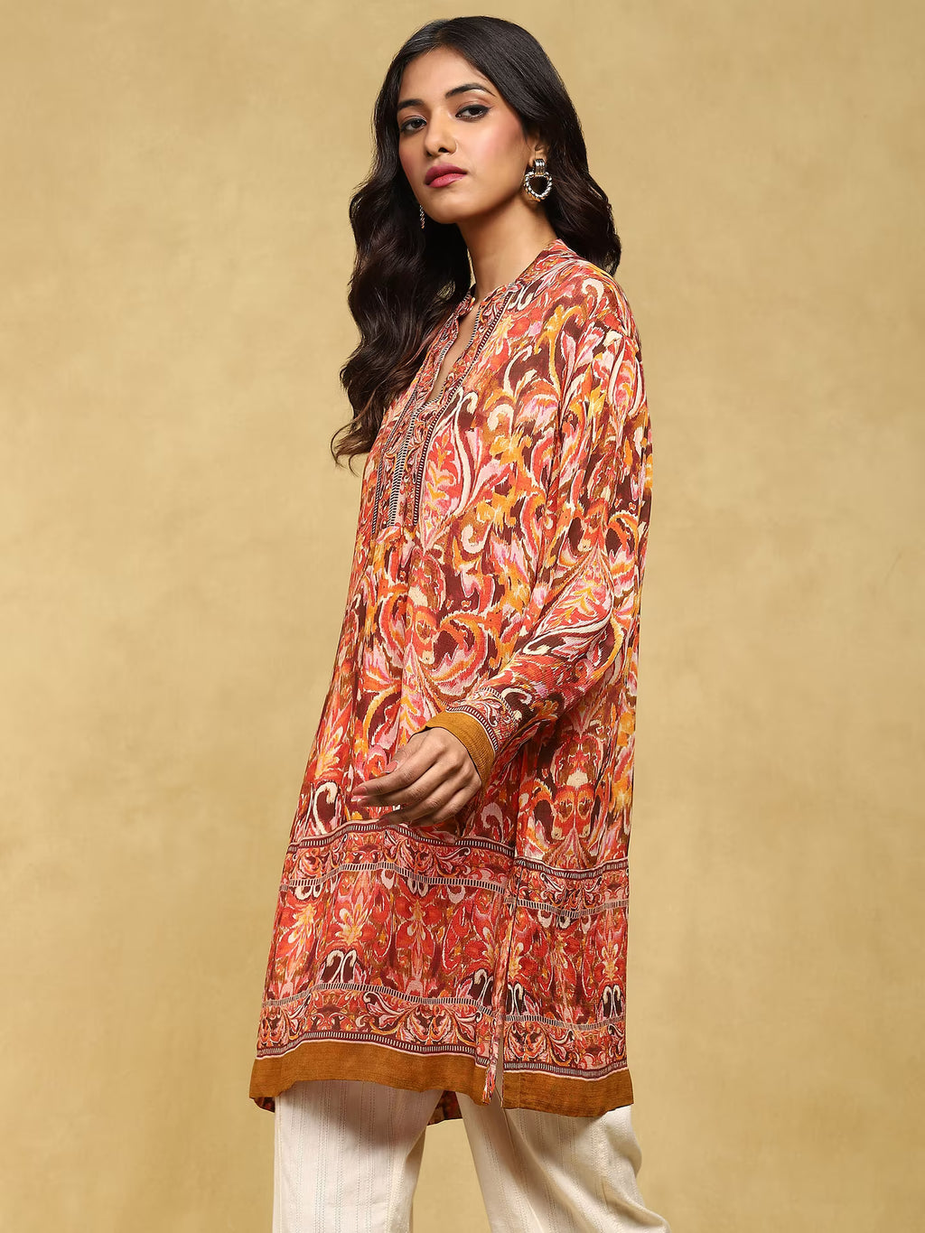 Woman wearing a patterned orange and brown shirt against a beige background