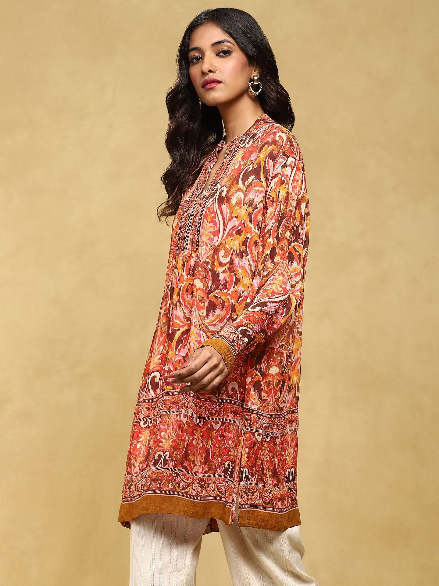 Woman wearing a patterned orange and brown shirt against a beige background