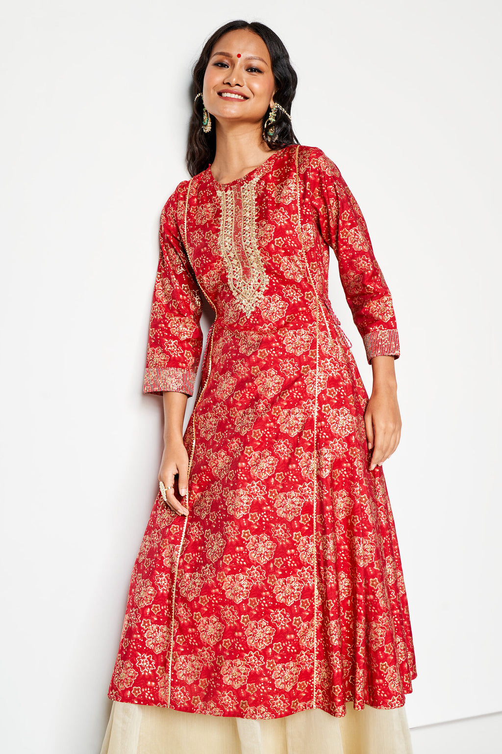 Woman wearing a red floral patterned kurta with a white background