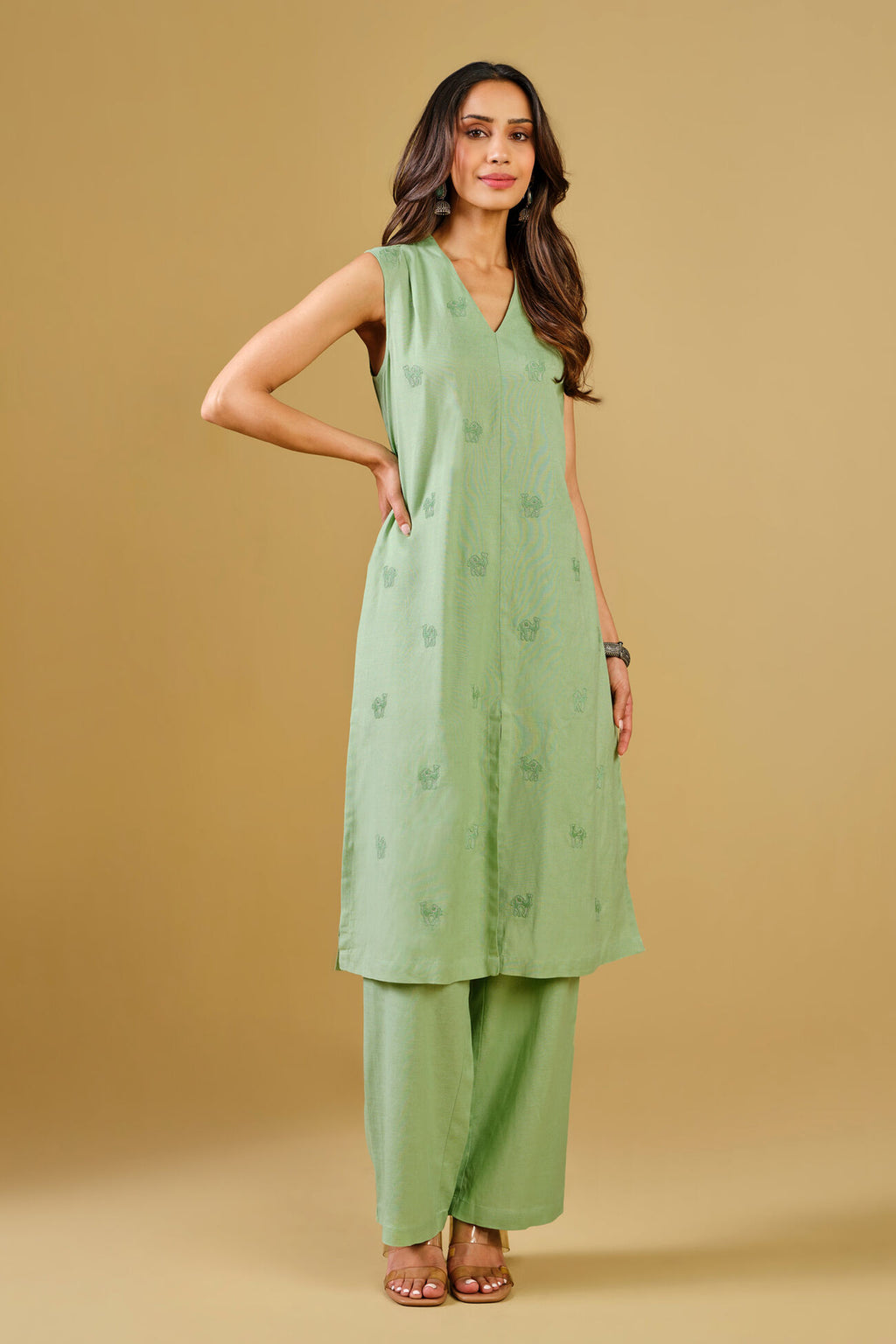 Woman wearing a green kurta with palazzo pants on a beige background