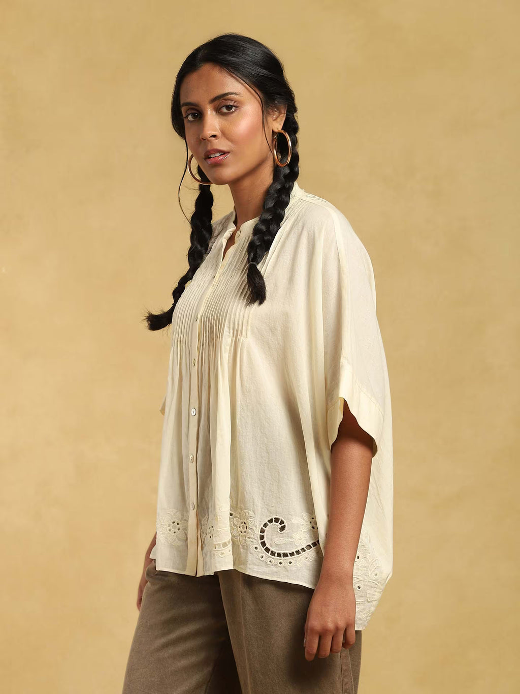 Woman wearing a light-colored blouse with intricate details on a beige background