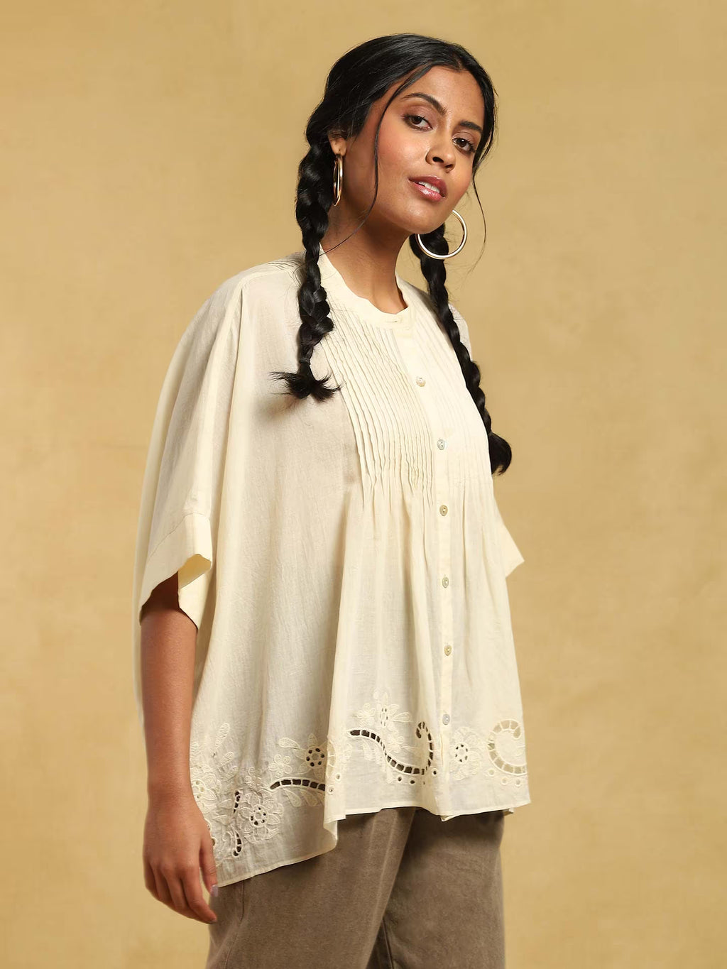 Woman wearing a white kurta with intricate designs on a beige background
