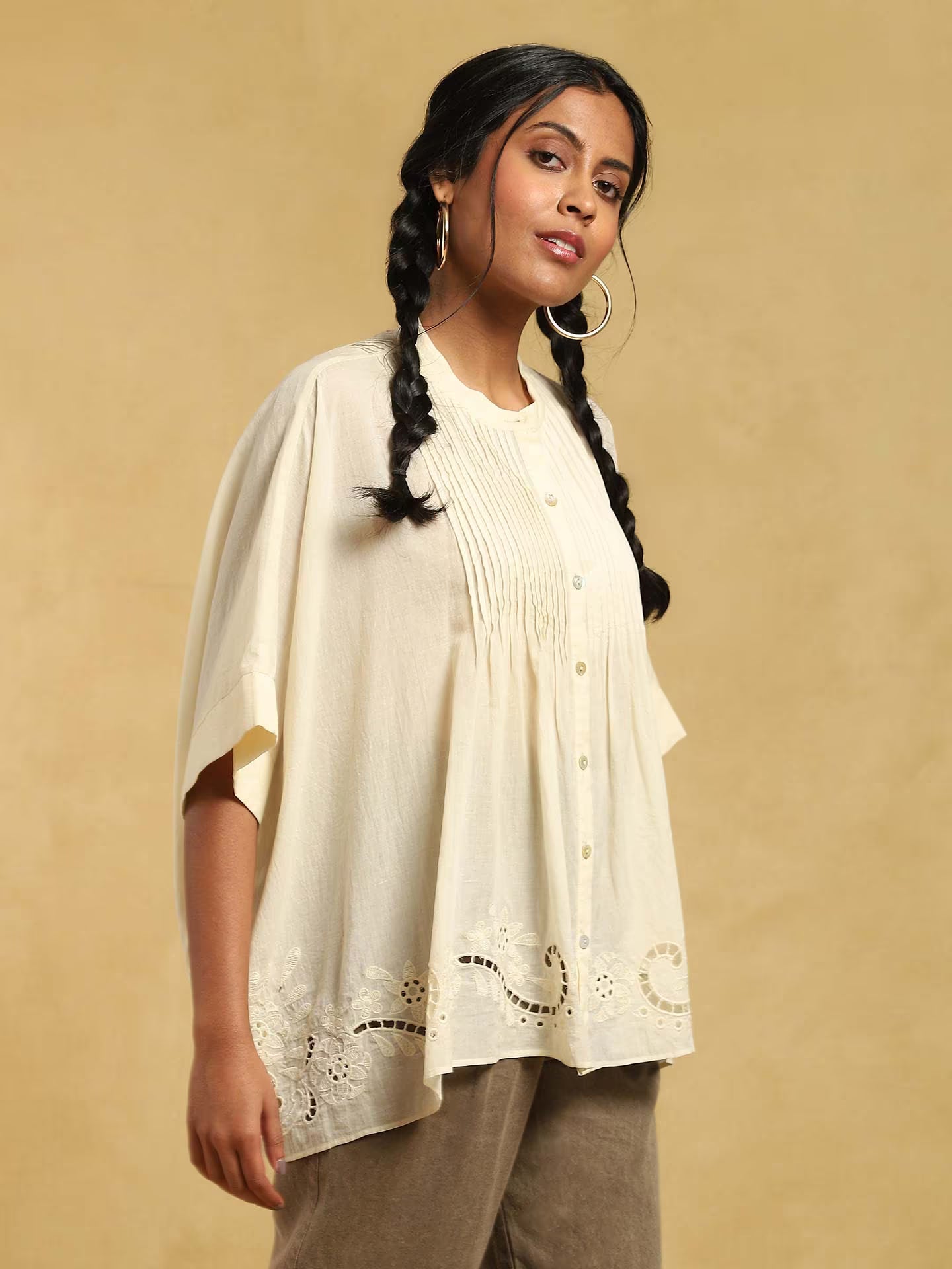 Woman wearing a white kurta with intricate designs on a beige background
