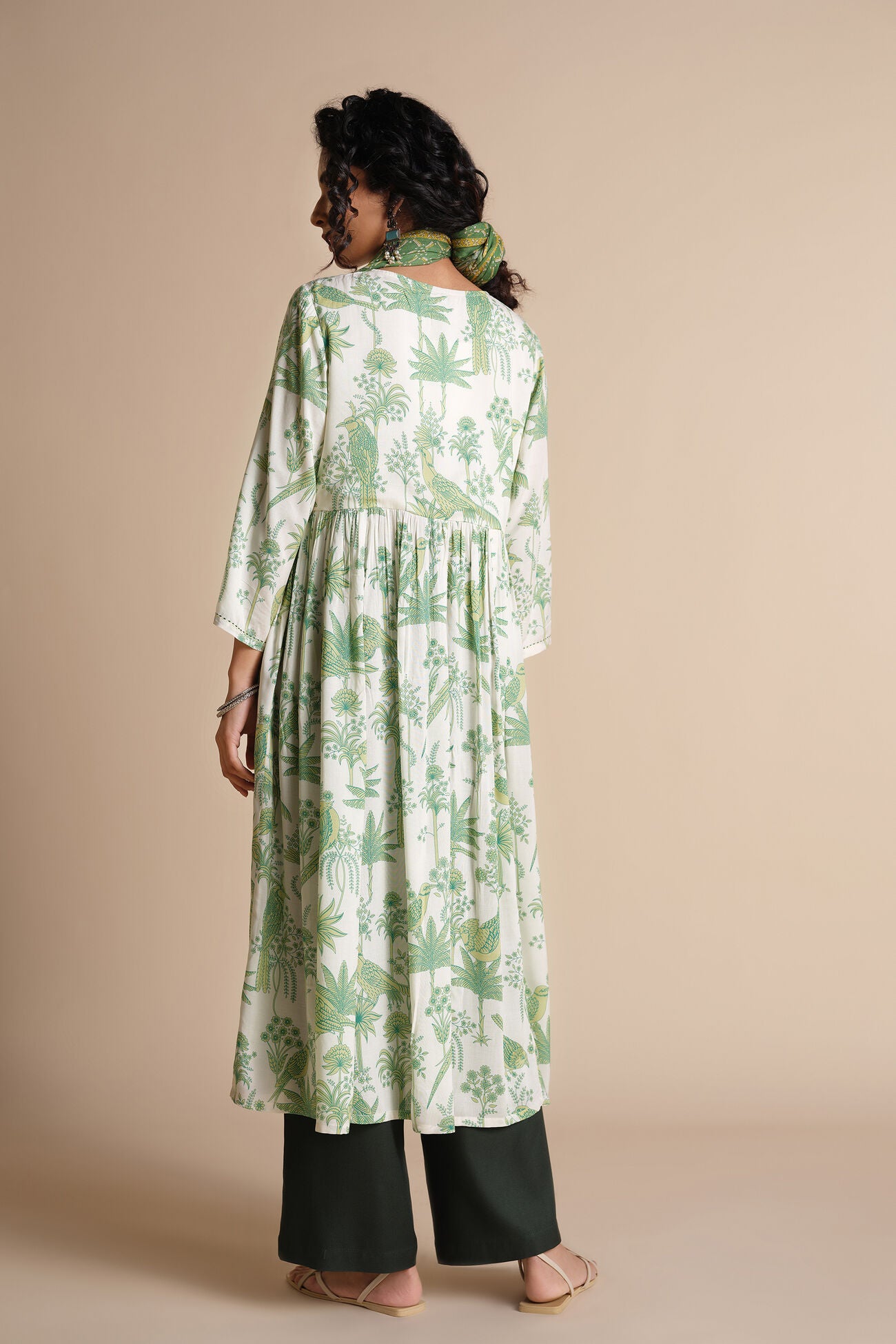 Woman wearing a green floral dress with a beige background